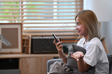 快乐的亚洲女人在客厅坐着时 有智能手机视频通话周末高清图片素材