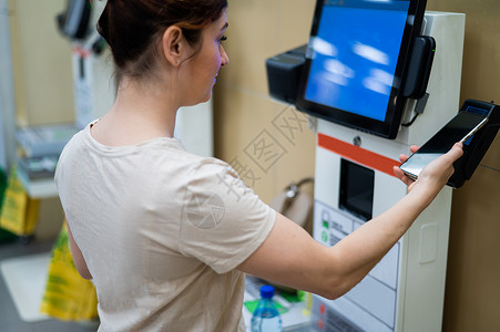 在自检柜台用智能手机买单的女士商业消费者机器服务客户工具扫描零售技术女性背景图片