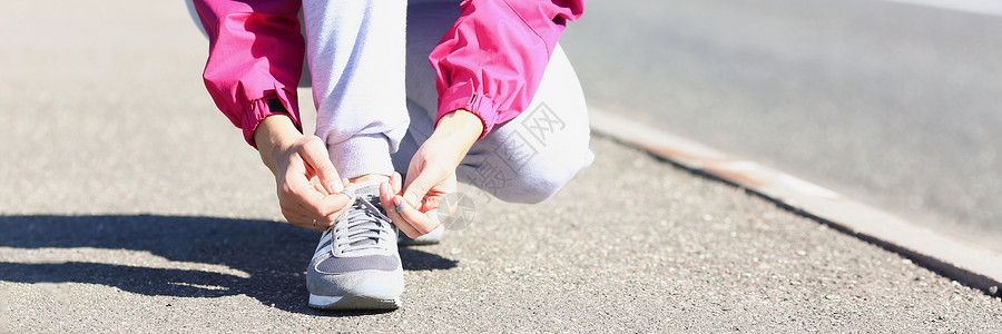 在公园进行新鲜空气培训前系鞋带的女跑者背景图片