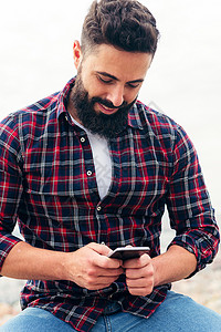 在手机上打短信的胡须男子短信社会互联网男人技术男性微笑水平拉丁阅读快乐的高清图片素材