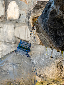 在一个公共来源用清泉水填充塑料瓶装的塑料瓶石头干旱生态喷泉全球生活方式环境运动矿物瓶子背景图片