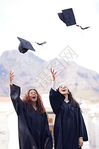 你越努力工作 奖赏就越高 两个年轻女子在毕业日就把帽子扔到空气里了背景图片