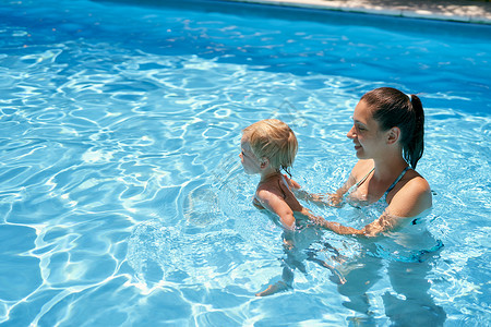 在游泳池里休息妈妈教一个小宝宝游泳游泳 在游泳池里有绿绿水背景