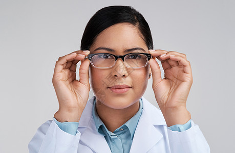 现在情况越来越明朗了 一位有吸引力的年轻女科学家在工作室戴眼镜 带着灰色背景的玻璃镜片被剪裁成肖像背景图片