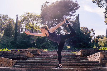 做运动女孩体育女运动员在公园做瑜伽平衡运动背景