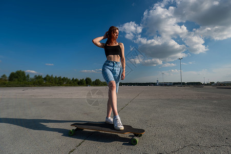 年轻的caucasian女人在外出长板的露天闲暇女性沥青骑术运动滑板平衡乐趣木板女孩背景图片