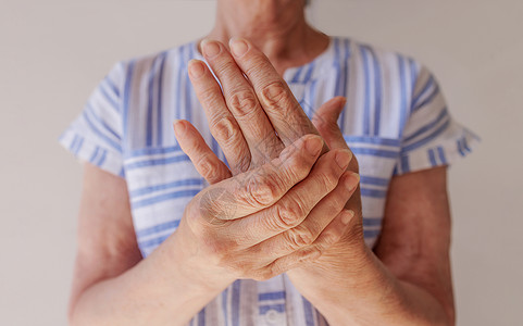 一位年长妇女因手部疼痛而受伤 紧贴地摸腕部高清图片