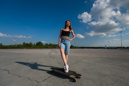 年轻的caucasian女人在外出长板的露天乐趣街道运动青年女孩阳光诡计女性城市平衡背景图片