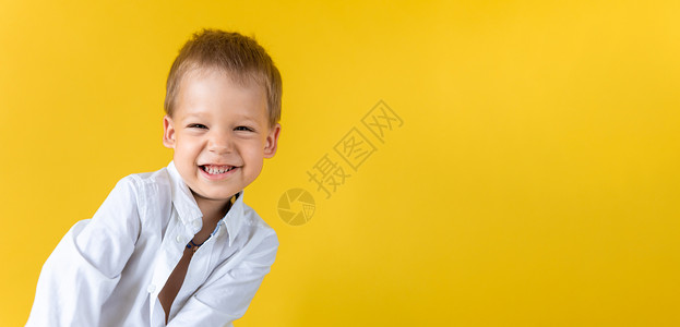 横幅滑稽的学龄前儿童男孩穿着未系扣子的衬衫 在黄色背景复制空间上微笑着眯起眼睛 快乐微笑的孩子回到学校 幼儿园 成功 动机 天才纸高清图片素材