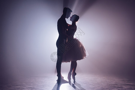 女演员浪漫专业芭蕾舞配对在黑暗的舞台互相仰望 年轻夫妇穿着经典礼服跳舞 每个运动都优雅和温柔不屈背景
