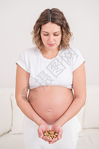 孕妇拿着一小撮核桃婴儿母性保健食物营养早餐腹部怀孕肚子饮食女士高清图片素材