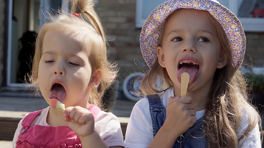 吃冰淇淋女孩三个可爱的小孩享用美味的冰淇淋甜筒 孩子吃西瓜冰棒 家庭花园里的孩子们的兄弟姐妹零食糖果 暑假炎热的天气晴天 童年 食品糖果手提背景