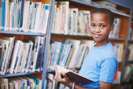 他喜欢看新故事 一位非裔美国人男孩的肖像 在图书馆里享受一本好书 很好背景图片