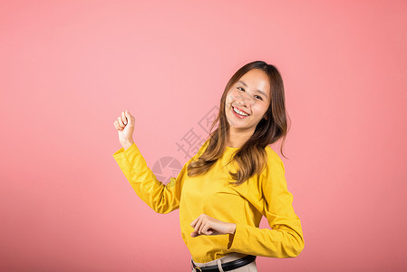 亚洲青年女子以鼓舞人心的面容表情和举起手来跳舞手势舞蹈家活力闲暇微笑情感女孩女士配饰姿势背景图片