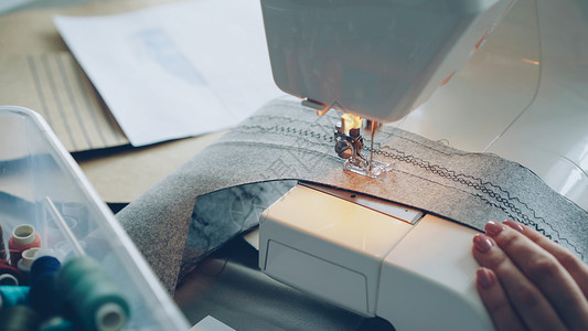 现代电动缝纫机的近身缝纫织物 女孩的修甲手和彩色缝纫线都可见一斑图片