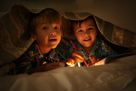 妈妈说光能驱除坏事 两兄弟躺在毯子下用手电筒给照片上色背景图片