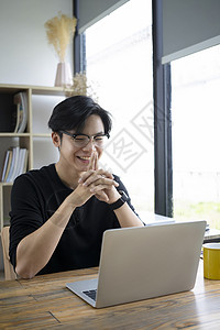 带着笔记本电脑在电视会议上微笑着的亚洲人房子高清图片素材
