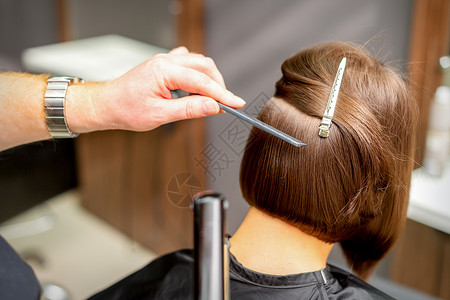 毛发画家正在清理黑发年轻女人的短发 在理发厅里用平板铁打近身 关上门治疗造型师工作室成人顾客梳子发型女孩女士头发沙龙高清图片素材