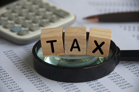 备案在放大镜上贴有标签的税字木块 税务调查概念 计算器和数字分析背景 税收概念;以及背景