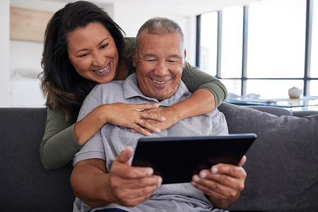 老年夫妇使用移动平板电脑技术 视频通话家人并在家里的沙发上与朋友交流 快乐的年迈祖父母放松 在线观看有趣的内容并热爱退休生活长椅高清图片素材