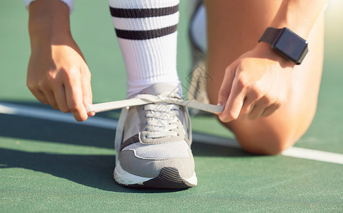 户外网鞋素材网球运动员在网球场上比赛前系鞋带 准备获胜 女运动员在网球比赛前将鞋带系在运动鞋上 训练 锻炼和享受户外运动的乐趣背景