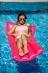 粉色女士的泳衣穿着粉红色比基尼泳衣的女人漂浮在可充气的粉色床垫上 Spf和防晒霜是被涂过的太阳镜火烈鸟游泳衣闲暇游泳温泉横幅娱乐身体泳装背景