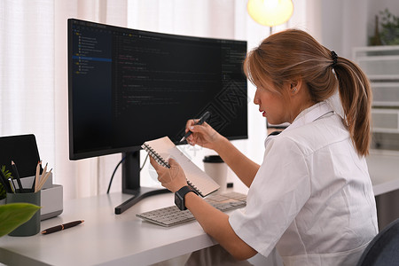 年轻女性编程员 在明亮现代办公室使用台式计算机编码数据工作电脑显示器职场设计师信息技术监视器代码屏幕企业家电脑程序背景