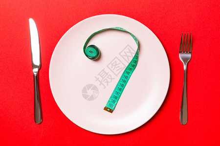 叉子和盘子上贴有彩色背景的测量胶带生活方式高清图片素材