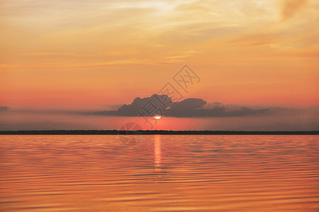 海中日落或日出 自然景观背景 红橙色云在天空中飞向阳光照亮水面 夜晚或早晨看到微笑和闪烁的太阳抽象的高清图片素材