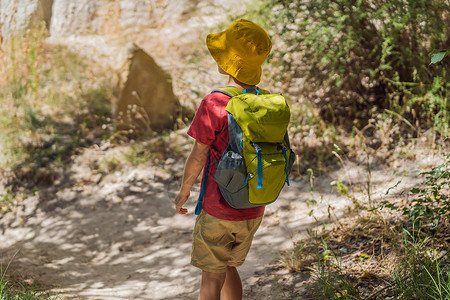 在土耳其卡帕多西亚的Goreme附近用岩石层和仙子洞穴探索山谷的男孩旅游者场景旅游地质学编队地标冒险儿子假期游客砂岩风景高清图片素材