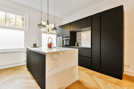 一个有黑柜子和白大理石岛的厨房沙发住宅窗户家具房子台面橱柜大理石财产装饰背景图片