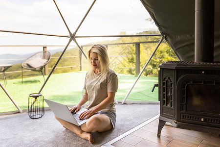 中年妇女在假期使用笔记本电脑在 Glamping 屋休息和消磨时间 假日圆顶帐篷 舒适 露营 hygge 生活方式概念商业视频庆背景图片