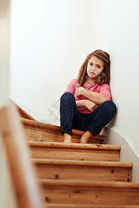我感到很孤单 一个小女孩 在家里坐在楼梯上看着悲伤的眼神独自的高清图片素材