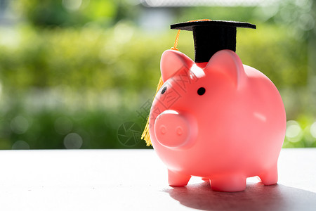 将钱币存到小猪银行和毕业上限 商业金融教育概念学生高清图片素材