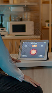 女人在家里看带有自动化照明系统的平板电脑灯泡控制经济屏幕女士互联网活力技术软件工具药片高清图片素材