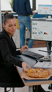 办公室送外卖中午休息的女商务人士在餐桌上吃饭吃披萨快餐纸袋职场咖啡送货邮递员数据企业家图表电脑人士背景