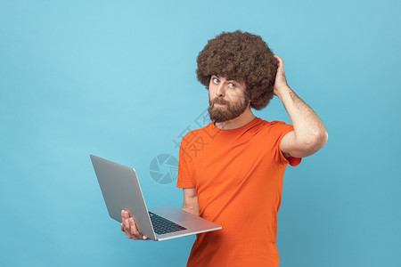 编程爆炸素材一个人拿着笔记本电脑 想着新的计划 抓他的后脑勺背景