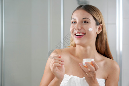 微笑的放松的女孩在脸颊上涂奶油 对有敏感皮肤的年轻人进行健康治疗镜子瑕疵容貌青少年清洁套路维修新鲜度拉丁中心背景图片