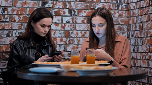 两个漂亮的女孩坐在咖啡厅里 和电话交谈 - 是的 先生城市的高清图片素材
