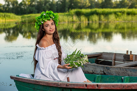 深色头发长发的女神 穿着白色古董礼服 坐在河中央的一条船上神话美人鱼魔法裙子花朵童话魅力成人海滩冒充女孩高清图片素材