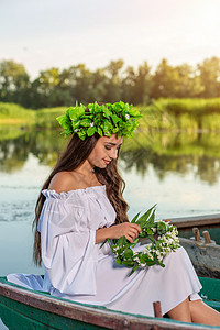 深色头发长发的女神 穿着白色古董礼服 坐在河中央的一条船上海滩神话美人鱼童话若虫女孩魅力魔法花朵冒充幻想高清图片素材
