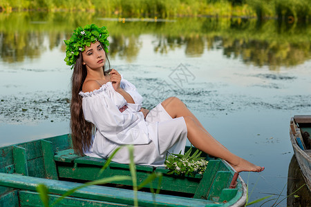 深色头发长发的女神 穿着白色古董礼服 坐在河中央的一条船上童话花朵裙子冒充女孩神话魅力海滩成人美人鱼白种人高清图片素材
