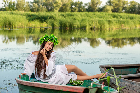 深色头发长发的女神 穿着白色古董礼服 坐在河中央的一条船上海滩若虫裙子童话女孩神话花朵魔法美人鱼冒充湿的高清图片素材