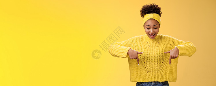 建军节宣传片头身穿毛衣头带 热情微笑 着迷的非洲裔美国女性印象深刻 她指着食指 喘着粗气 惊讶地着迷 酷酷的惊心动魄的宣传片 站立的黄色背景青背景