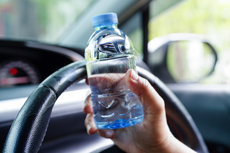 喝冷水亚洲女司机在汽车中饮用冷水 危险且有发生事故的危险电话讲话食物运输车辆手机风险面包碰撞旅行背景