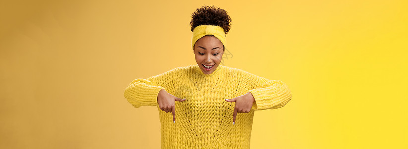 建军节宣传片头身穿毛衣头带 热情微笑 着迷的非洲裔美国女性印象深刻 她指着食指 喘着粗气 惊讶地着迷 酷酷的惊心动魄的宣传片 站立的黄色背景护背景