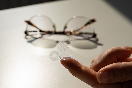 在白色桌子上的眼镜背景下 女性食指上隐形眼镜的特写塑料女士女孩手臂护理眼科援助眼球近视散光柔软的高清图片素材