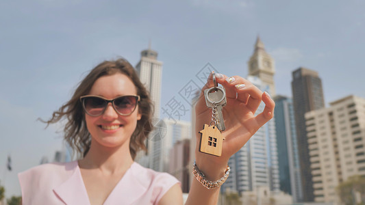 在迪拜摩天大楼的背景下 女孩拥有新房子的钥匙 校对 Portnoy贷款销售财产男人住宅商务礼物保险公寓成人新的高清图片素材