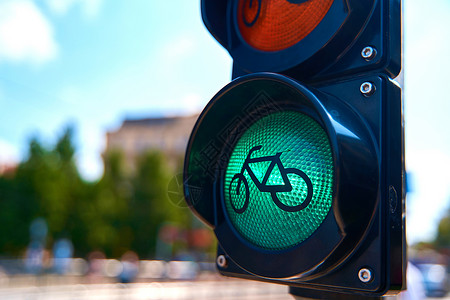 信号灯路口骑自行车者的交通信号灯的特写 它发出绿色光 一辆自行车出现在红绿灯处背景