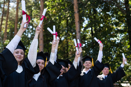 一群穿着长袍的毕业生用户外文凭举起手来 年老学生男性高清图片素材